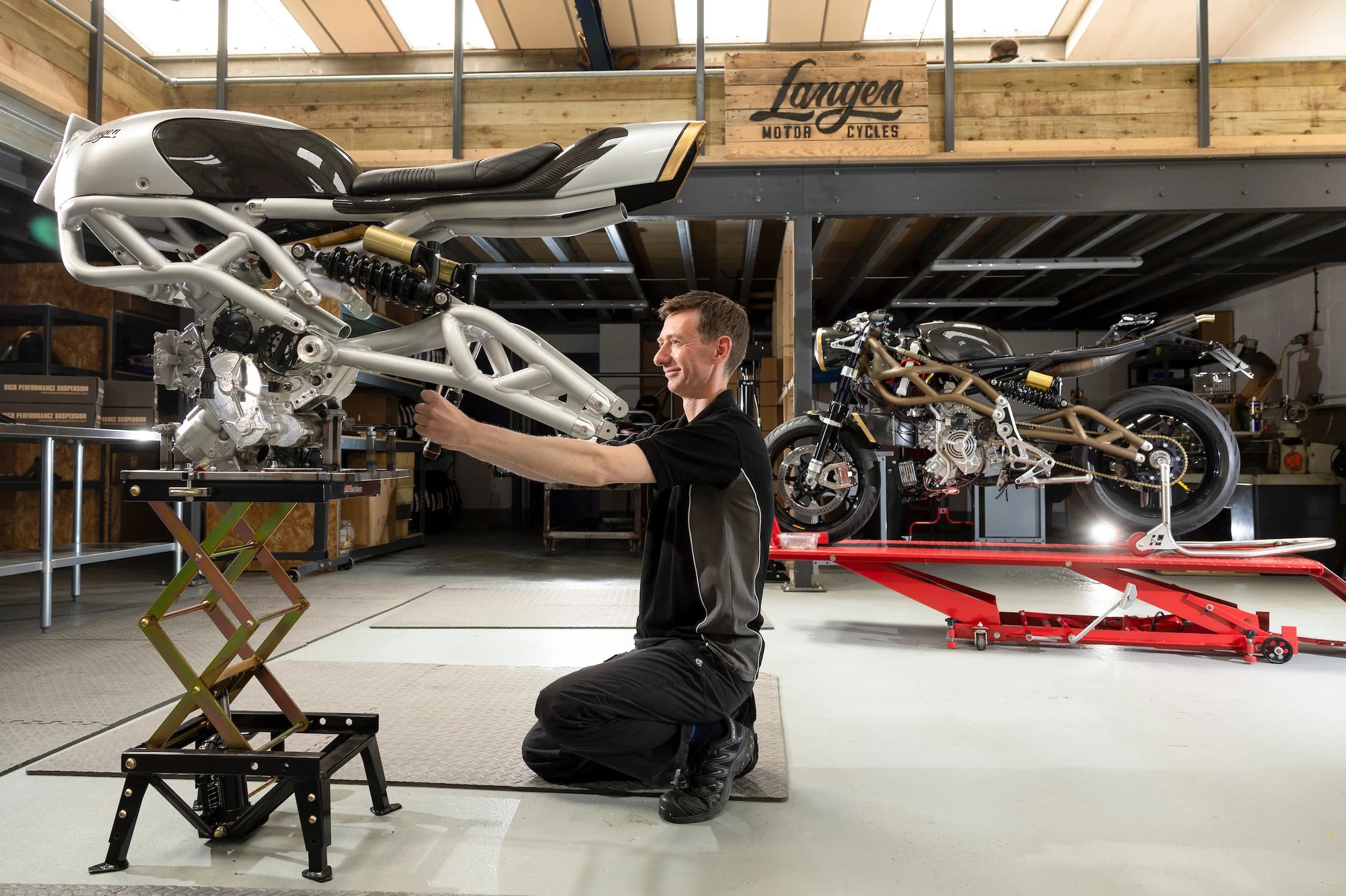 A Langen engineer holding a Two Stroke chassis aloft in the workshop